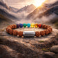 7 chakra rudraksha bracelet displayed on a rocky surface with mountains and sunset in the background.