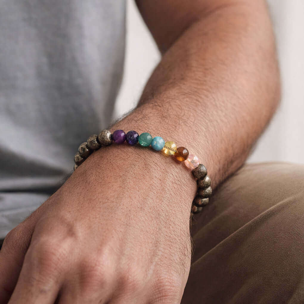 Magnet 7 Chakra With Pyrite Bracelet worn on a man's wrist, showcasing colorful chakra stones and pyrite.